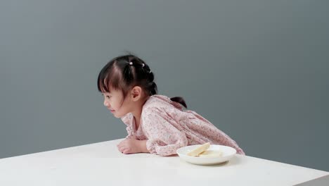 Niño-Con-Vestido-Colgado-En-Una-Mesa-Blanca-Con-Plato-Con-Dulces