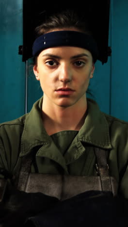 female welder standing with arm crossed in workshop