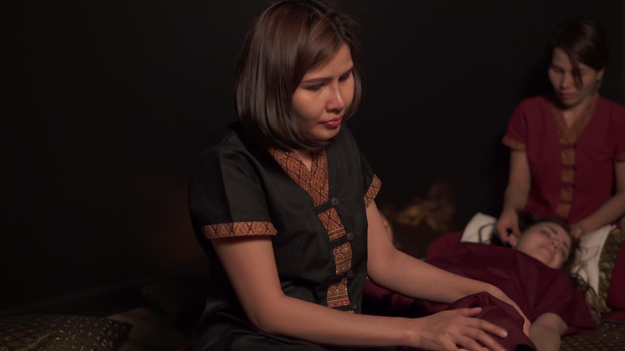 두 명의 여성 태국 치료사가 스파 살롱에서 한 여성에게 마사지를 하고 있습니다. 두 손으로 다리와 머리의 태국 마사지 4k  ⁇