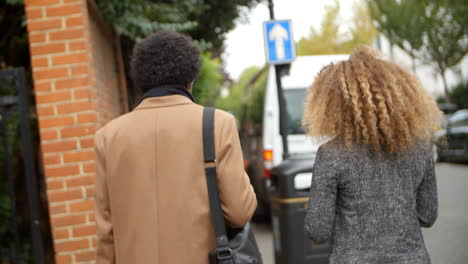 Rear-View-Of-Stylish-Couple-Walking-Along-Street-In-City