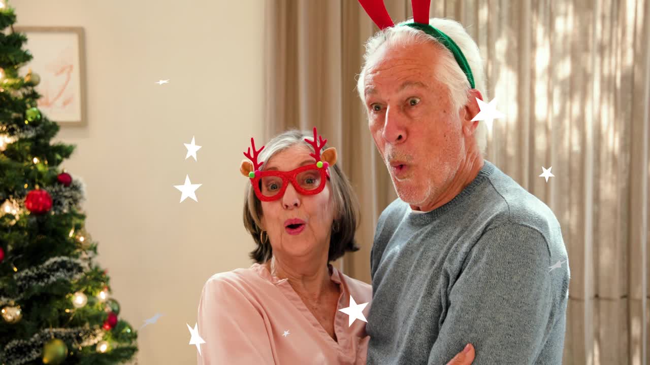 Senior couple turning on camera cue, hugging, laughing for holiday ad with sparkling stars drifting