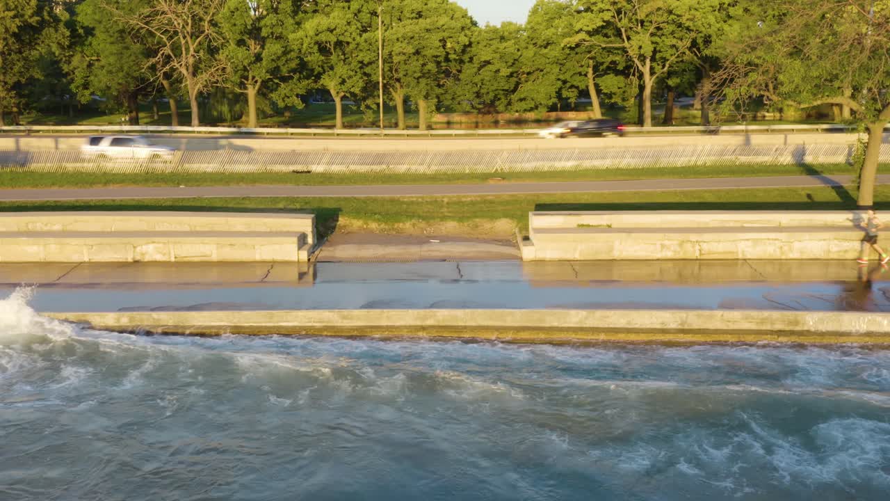 toma aérea estática de personas haciendo ejercicio a lo largo del camino a orillas del lago de chicago mientras las olas chocan contra el camino debido a los altos niveles de agua