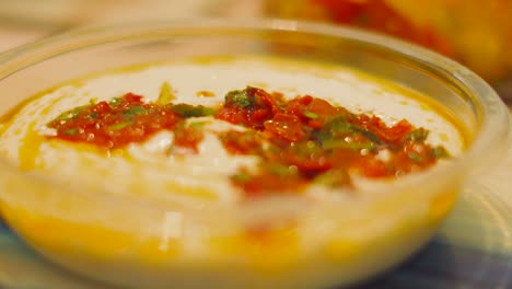 hand dipping fresh bread into garlic aioli sauce with sunblushed tomatoes on top. delicious healthy snack