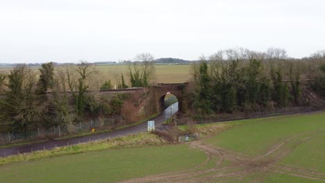 Drone-Moviéndose-Hacia-Un-Puente-Ferroviario-En-El-Campo-En-Un-Pueblo-De-Kent