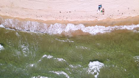 Drohnenclip-In-Zeitlupe-über-Einem-Wunderschönen-Strand-Mit-Kristallklarem-Wasser-Und-Wellen,-Die-Auf-Dem-Boden-In-Keramoti,-Kavala,-Nordgriechenland-Zermalmen