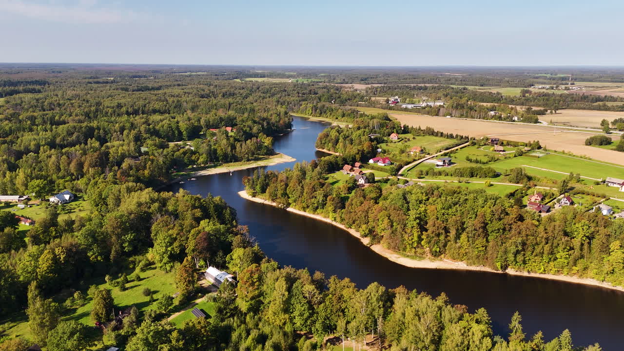 Drone wide ascend over Daugava River with surrounding trees and open fields, Koknese Latvia
