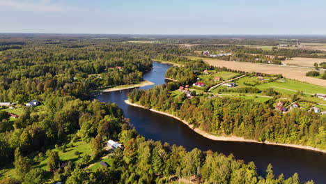 drone wide ascend over daugava river with surrounding trees and open fields, koknese latvia