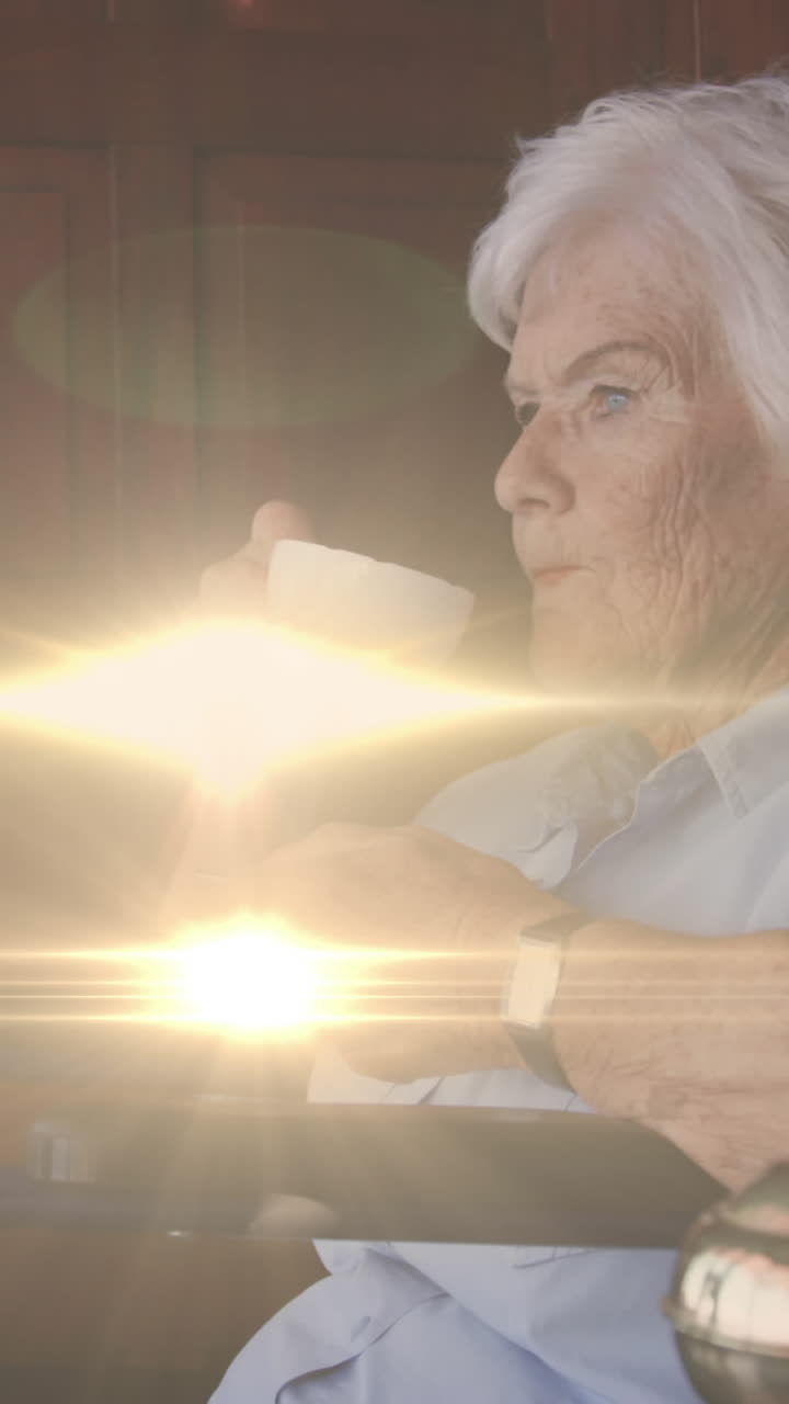 Animation of light moving over senior caucasian woman in wheelchair drinking coffee