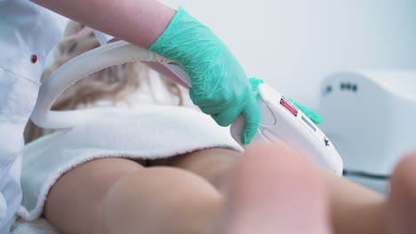 skilled dermatologist removes hair from woman leg in clinic