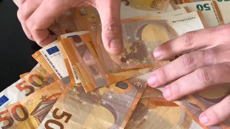 hands playing with a giant stack of 50 € banknotes