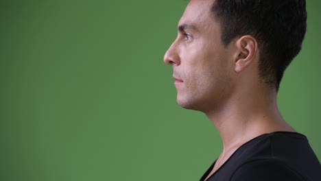 young handsome hispanic man against green background