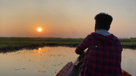 Silhouette-Eines-Mannes,-Der-Auf-Dem-Bug-Des-Bootes-Sitzt-Und-Den-Sonnenaufgang-Friedlich-Beobachtet,-Zeitlupe