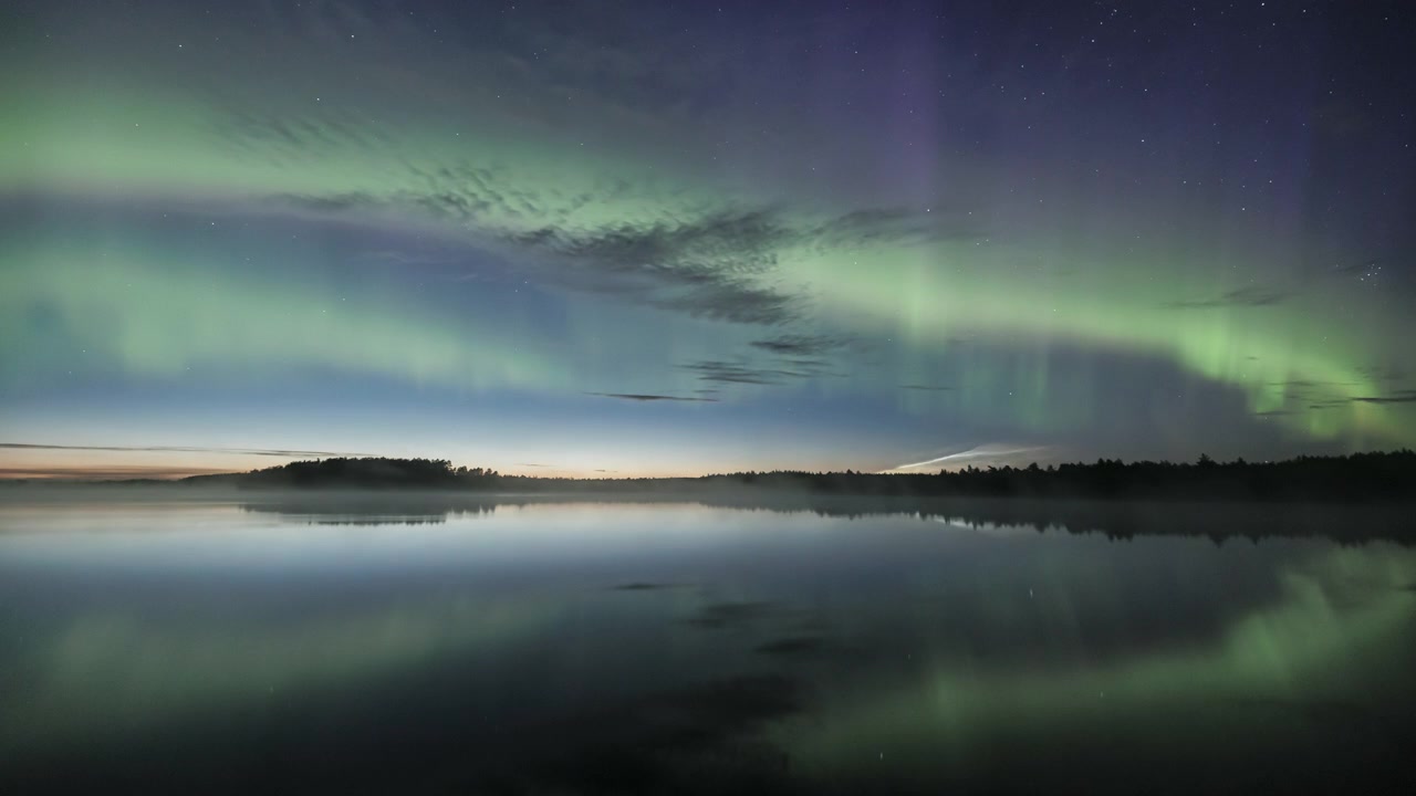 Time lapse av norrsken som speglas i en stilla sjö