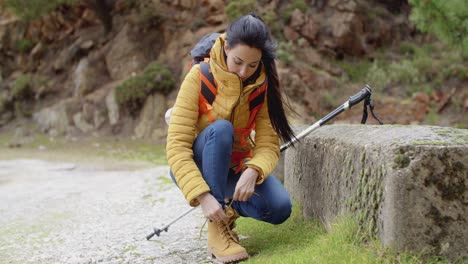 una mujer excursionista atando sus cordones