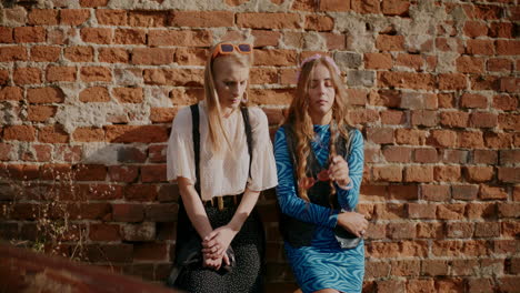 two friends posing against a brick wall