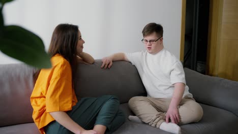 young downs syndrome couple or siblings talk while sitting on sofa