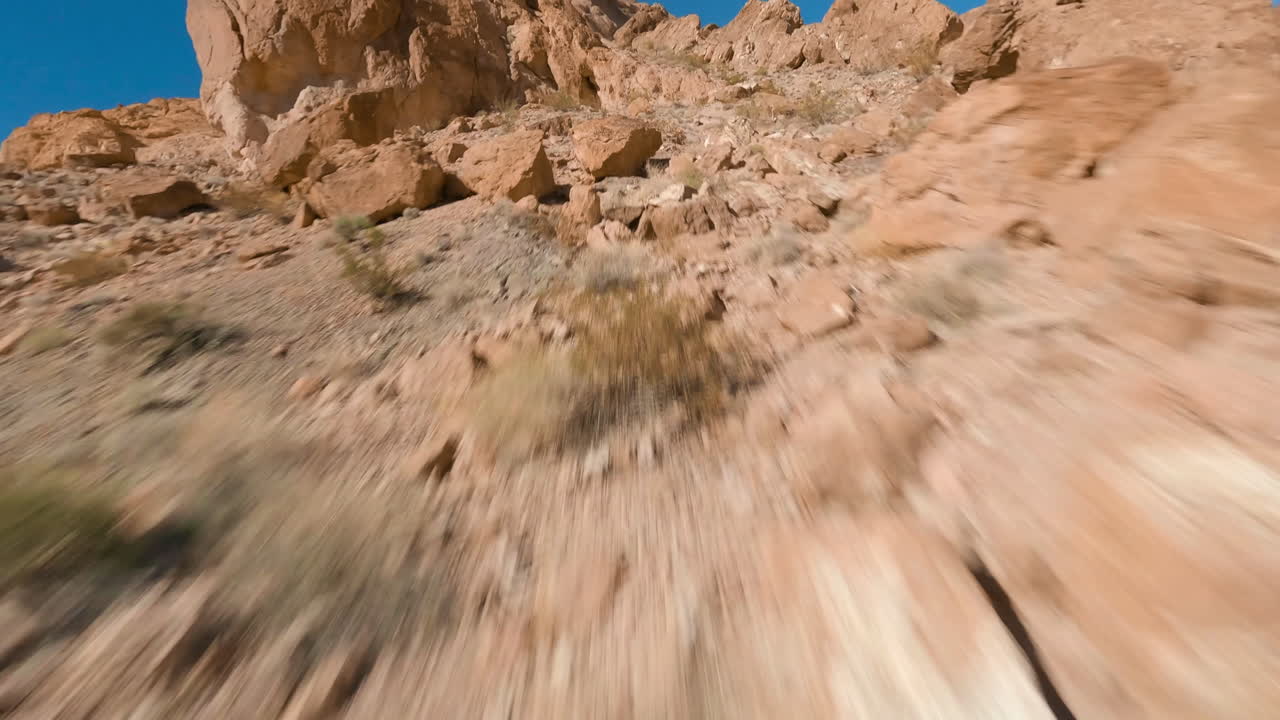 Drone FPV che vola attraverso un paesaggio desertico in una giornata di sole.