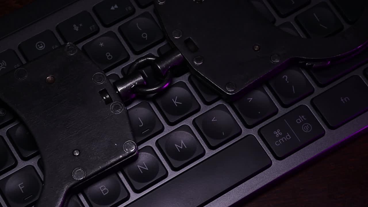 Handcuffs resting on a dark keyboard illuminated by blue light, symbolizing crime, justice, and law enforcement in a digital age with a focus on security and technology