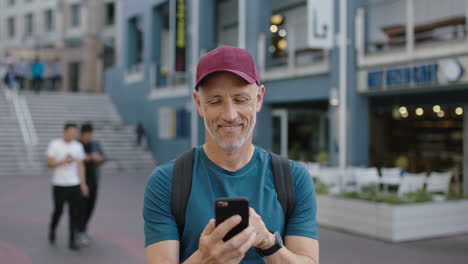 portrait of mature attractive caucasian tourist man wearing hat using smartphone app texting browsing enjoying vacation travel