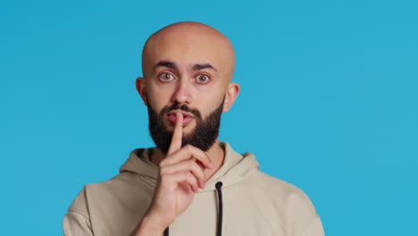 Middle-eastern-man-doing-hush-silence-symbol-in-studio