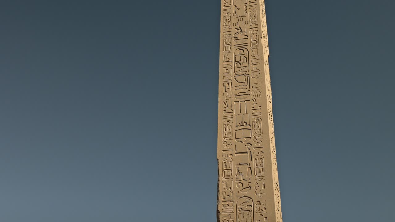 Muinainen egyptiläinen obeliski hieroglyfeillä sinistä taivasta vasten