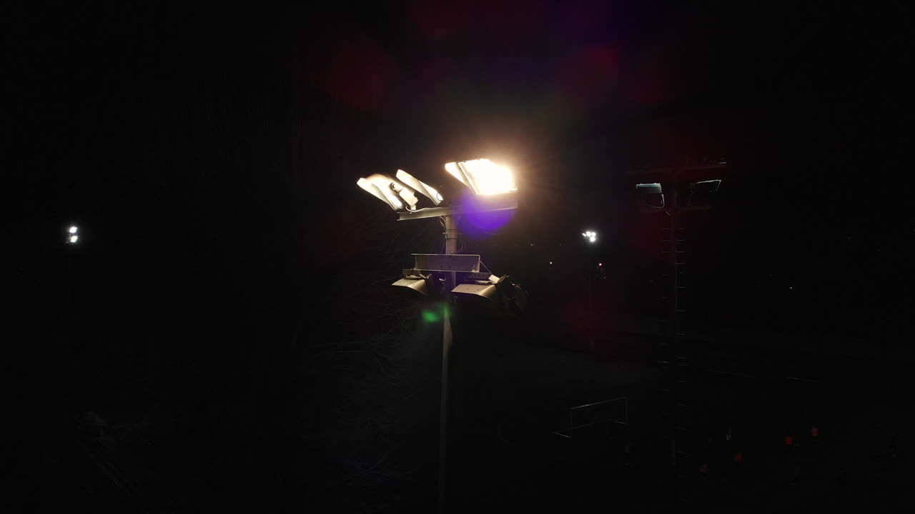 toma aérea volando hacia reflectores en un campo de fútbol, recibiendo bengalas de colores