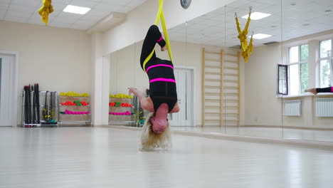 la chica en la lección de antigravedad en aero yoga en los lienzos hace una rotación boca abajo en el aire. disparo de cámara en cámara lenta