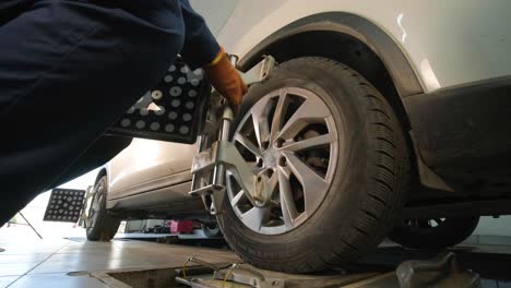 auto mechanic installing sensor during suspension adjustment and automobile wheel alignment work at repair service station. close up