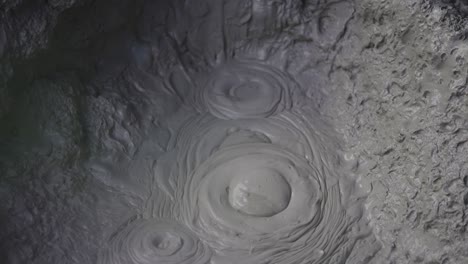 boiling hot geothermal volcanic mud pool, closeup shot steamy lake bubbling mud and steam satisfying symmetry