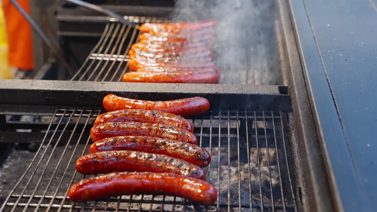 Sausages browning above hot grates with warm rising heat creating vivid roasted edges and texture