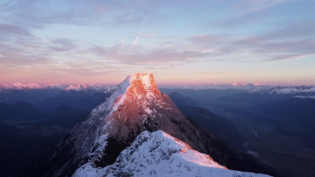hermosa cima de la montaña alpina en la puesta del sol hora de oro resplandor púrpura, valles y cadenas nevadas en la distancia