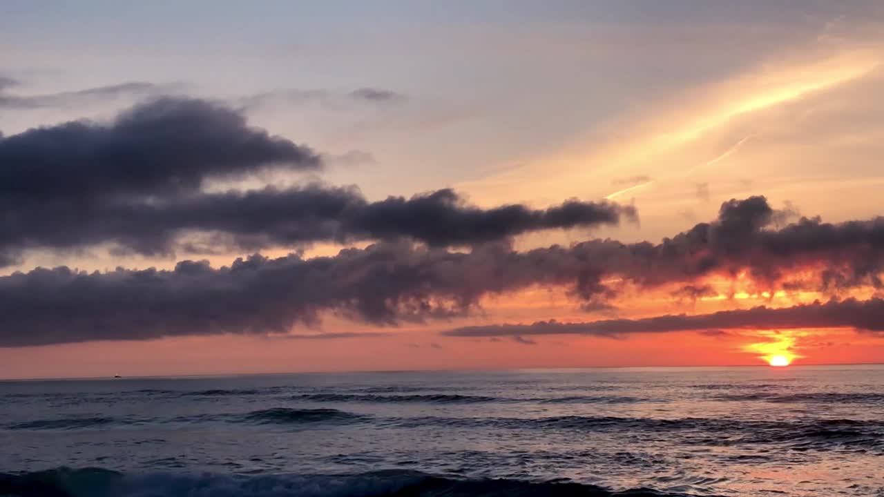 Sunset at Basttendorf Beach in Charleston, Oregon. A seagull flies toward the camera against an orange and blue sky.