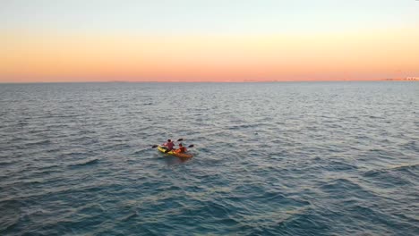 a couple kayak across the beautiful persian gulf off the abu dhabi coast during marvelous sunset