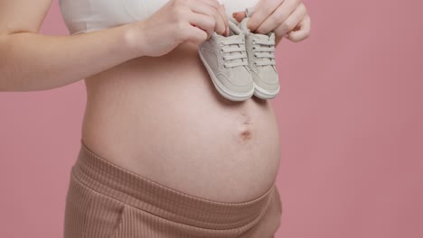 pregnant woman holding baby shoes