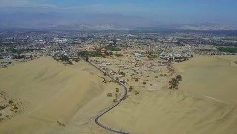 city of ica near huacachina oasis with road leading to the city between sand dunes in peru, south america