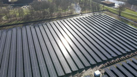aerial of bright sun reflection shining on a large solar panel field in a rural area