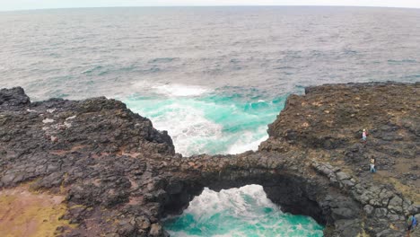 Group-of-tourists-standing-on-a-rock-cliff-sight-seeing-at-the-Pont-naturel-in-Mauritius