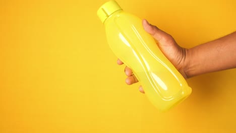 person holding a bright yellow plastic water bottle