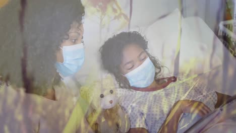 Animation-of-grass-over-biracial-mother-with-face-masks-and-her-daughter-lying-in-hospital