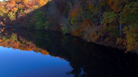 An-aerial-view-over-a-reflective-lake-in-the-morning-with-colorful-autumn-trees