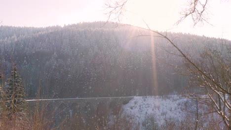 sun shining on a railway viaduct over a mountain valley,falling snow