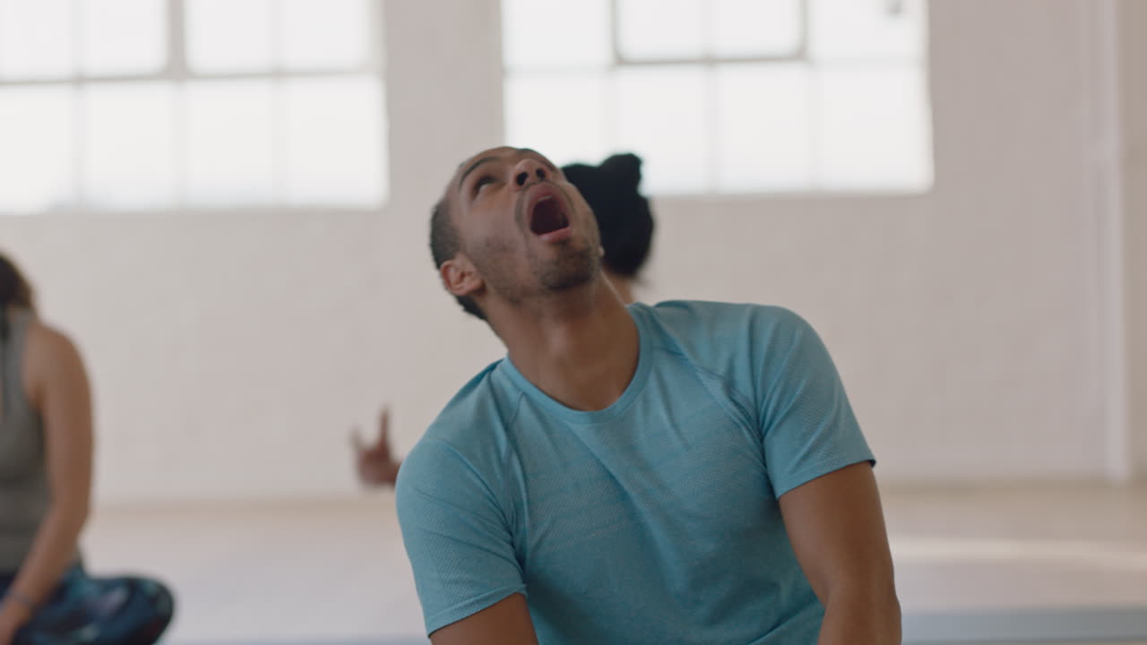 clase de yoga atractivo hombre hispano que parece aburrido bostezando esperando en el gimnasio