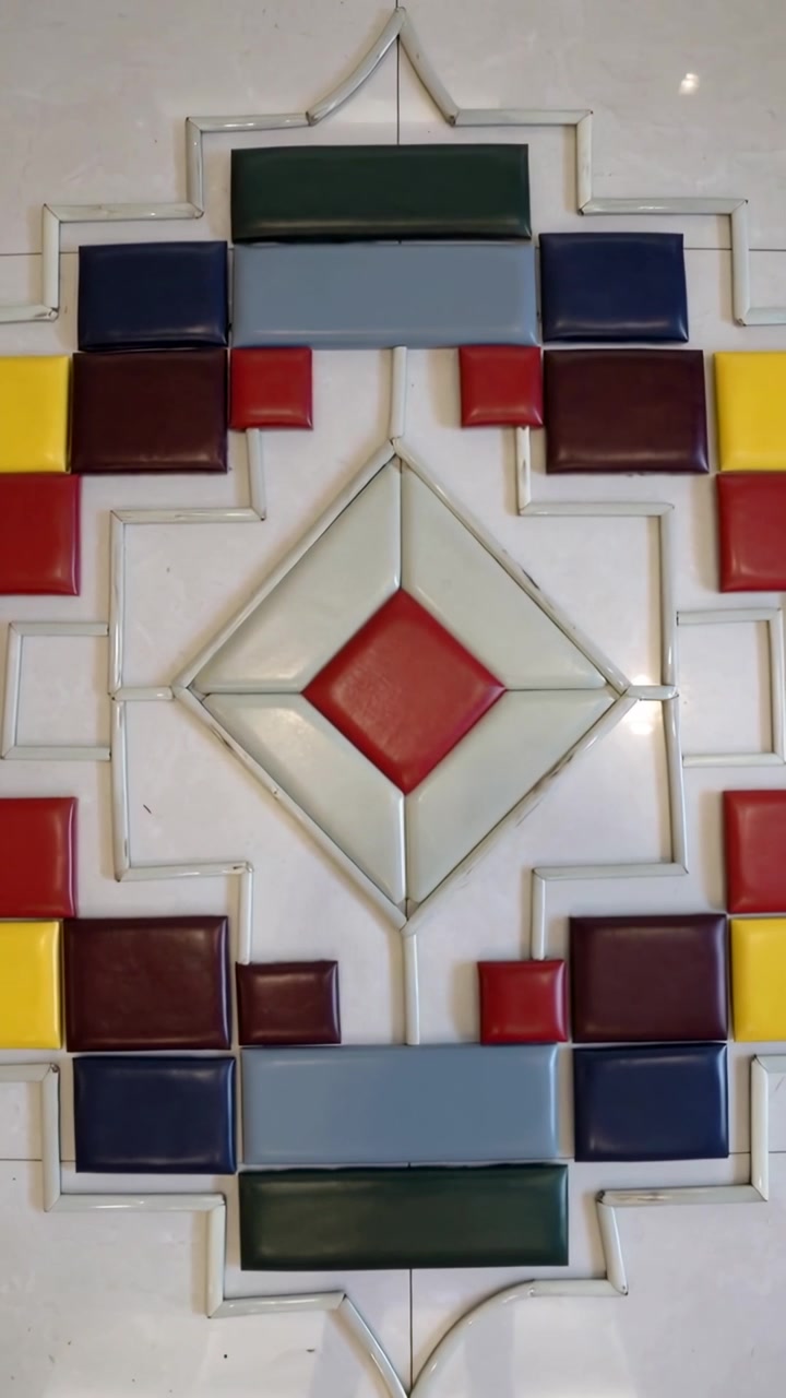 Video vertical: Cámara con paneo ascendente revelando un panel de azulejos cerámicos en la pared, exhibiendo un diamante rojo