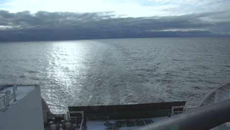 view from the stern of a ship or ferry, leaving a wake in the cloudy sea
