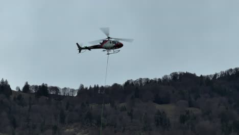 helicóptero en vuelo cerca de walensee, weesen, suiza, con un telón de fondo de exuberantes bosques de primavera temprana en las laderas de las montañas