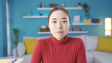 young asian woman looking at laptop, looking at camera, making serious facial expression.