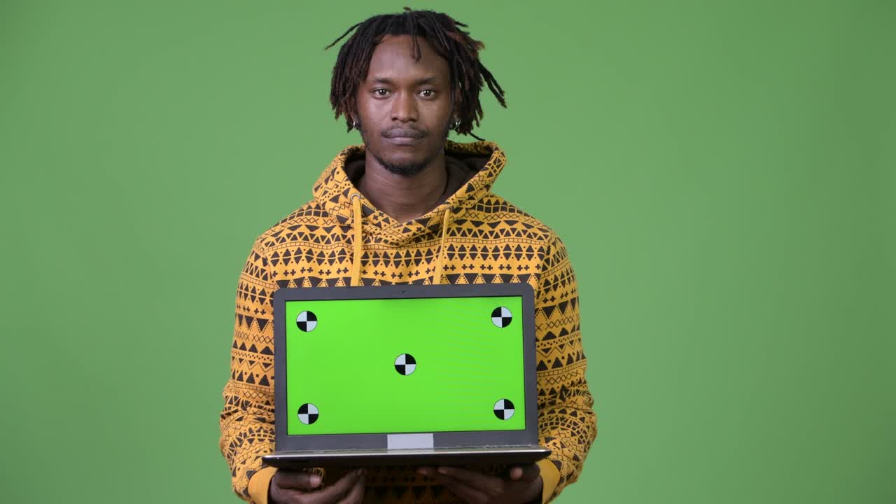Jovem homem africano bonito mostrando laptop