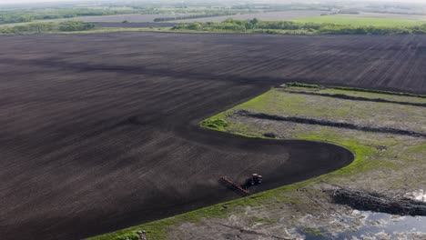 aerial shot of tractor cultivating large unplanted field