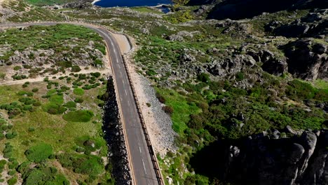 Aerial-view-of-a-winding-road-leading-to-a-stunning-lagoon-in-Serra-da-Estrela,-Portugal