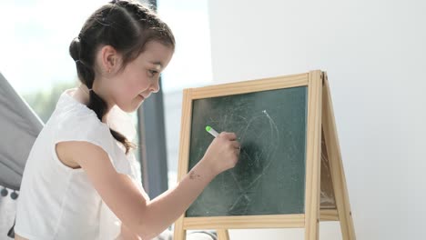 young girl drawing a heart on a chalkboard